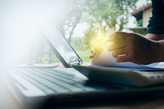 Professional working with business documents, laptop, and tablet in an outdoor natural light setting, concept of remote work, freelance lifestyle, and mobile office productivity.