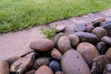 River pebbles are placed as a decorative accent over the drainage channel between the lawn and the footpath © Satakorn