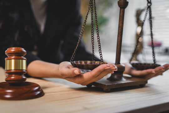 Lawyer's hands balancing scales of justice, representing legal equality, fairness, and law firm consultation. Gavel on table.