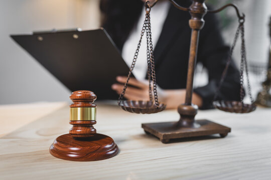Gavel and scales of justice with lawyer working. Gavel and scales of justice on a wooden desk with a person working on legal documents, representing law, justice, and authority.