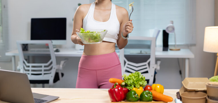 Woman eating healthy salad for fitness lifestyle and nutrition. Woman preparing and eating fresh salad at home, organic diet, and healthy living for a fit body.