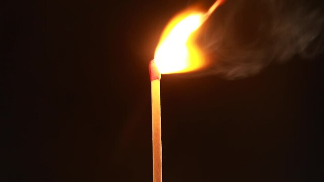 Burning match with bright flame on dark background as an abstract concept of life consumption and aging