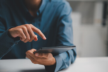 Businessman holding digital tablet and pointing finger at touchscreen while working in office. © MarkFinal