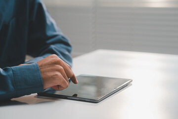 Close up of businessman hand touching and interacting with digital tablet screen on white desk. © MarkFinal