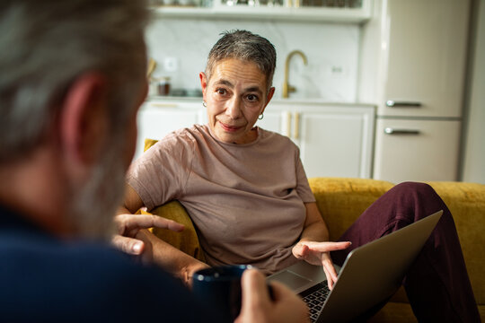 Senior woman talking with man while using laptop at home