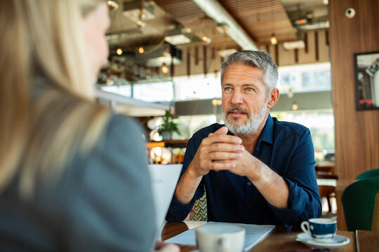 Mature man discussing business with colleague in cafe