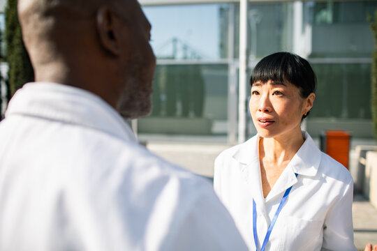 Female doctor talking with colleague outside hospital