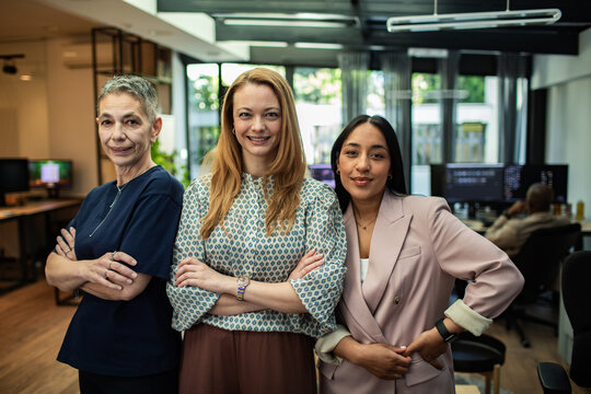 Three confident businesswomen posing together in open office