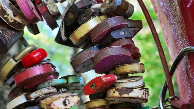 Colorful rusty love padlocks hang together as a symbol of eternal love in a park.