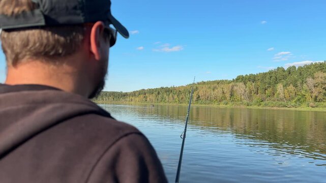 Rear view of fisherman with spinning rod on a calm autumn river