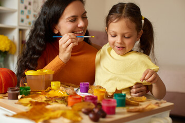 Naklejka premium Mother and daughter painting autumn leaves creating art