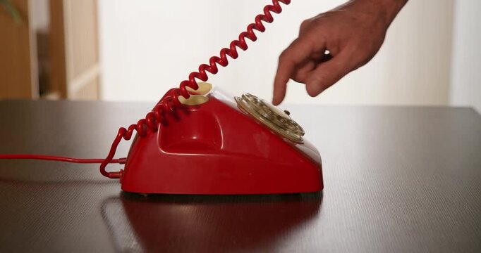 Dialing Back Time: A hand reaches out to dial a retro red rotary telephone, a nostalgic connection to communication's past.