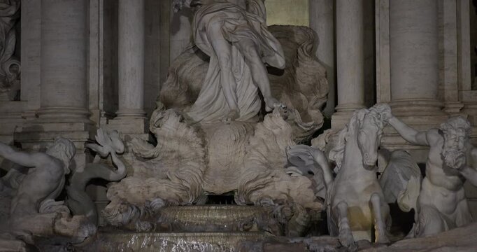 Detail view of the sculpted tritons and sea horses at Trevi Fountain at night in Rome.