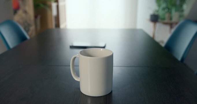 Morning Coffee Break: A solitary white mug sits on a dark table, a smartphone placed nearby, suggesting a quiet moment of contemplation before the day's demands.
