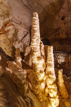 Stalactites and stalagmites in a cave Grotta di Monte Cucco in Umbria, Italy. Brown stones and crystalline deposits jut upwards.