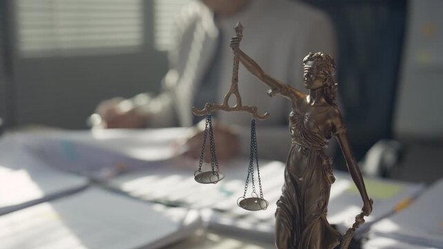 Scales of Justice with Lady Justice Statue and Legal Professional in Law Office