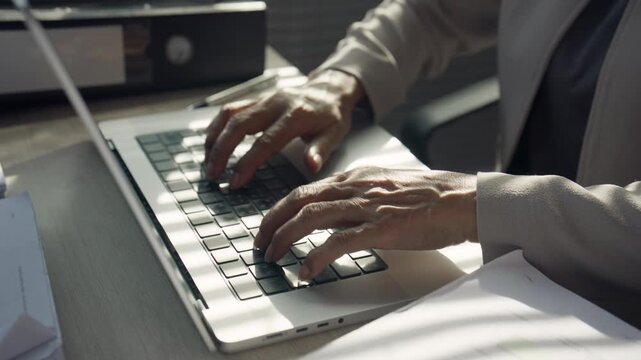 Business Professional Typing on Laptop at Busy Office Desk
