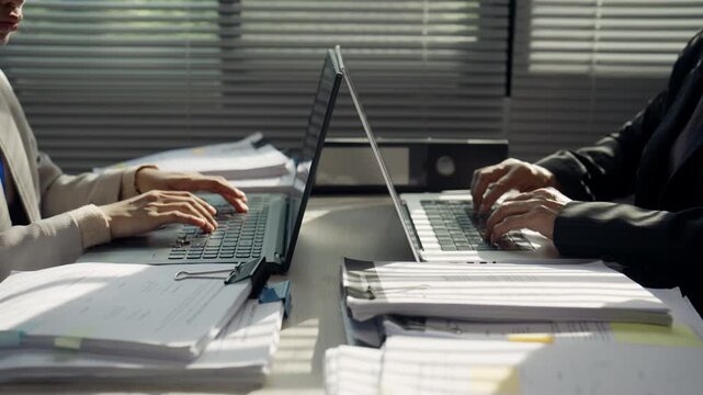 Business Professionals Working Face to Face on Laptops with Office Documents