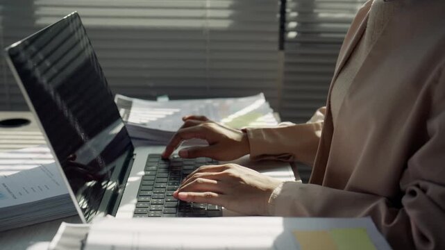 Busy Businesswoman Working on Laptop with Documents at Office Desk