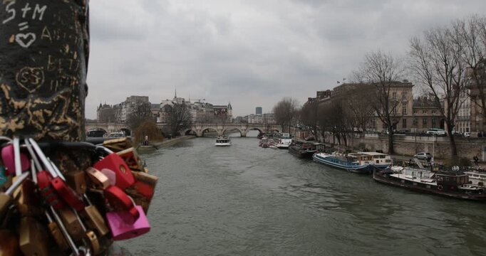 Love locks overlooking the Seine River in Paris France,Colorful love locks attached to a bridge overlooking the Seine River, with boats and historic riverside architecture in Paris, France.