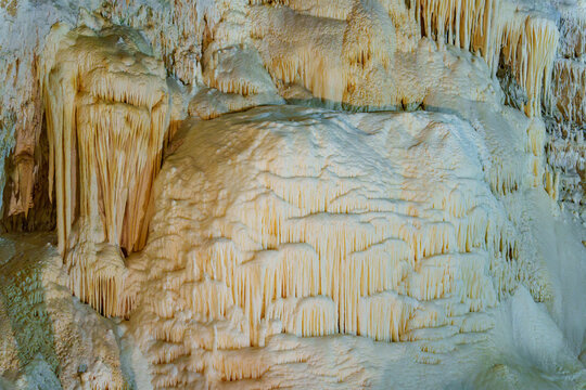 Whimsical stalagmites rise from cavern floor. Gentle light highlights rugged textures. Cave walls glow with muted, natural tones. Ancient formations stand silent and grand. Ideal for fantasy, nature.
