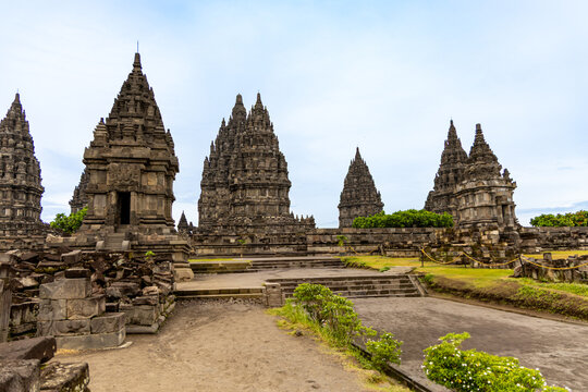 Prambanan Temple in Central Java, Indonesia. A vast 9th-century Hindu temple complex with intricate stone spires, sculptures, and ancient ruins under a cloudy sky.