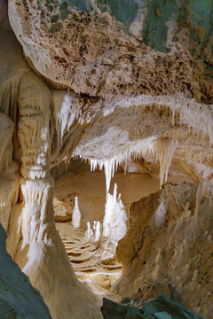 Passageways wind through the cave amidst various salt formations including stalactites and stalagmites in the Umbria region of Italy. The deposits feature whimsical shapes and diverse textures.