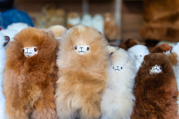 Fototapeta premium Fluffy alpaca plush toys displayed at a traditional souvenir market in Lima, Peru