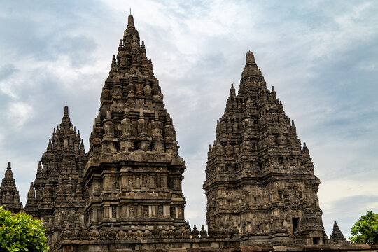 Prambanan Temple in Central Java, Indonesia. A vast 9th-century Hindu temple complex with intricate stone spires, sculptures, and ancient ruins under a cloudy sky.