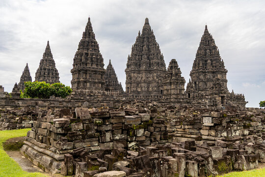 Prambanan Temple in Central Java, Indonesia. A vast 9th-century Hindu temple complex with intricate stone spires, sculptures, and ancient ruins under a cloudy sky.