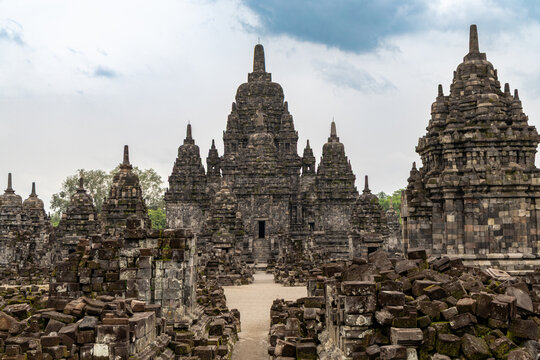Prambanan Temple in Central Java, Indonesia. A vast 9th-century Hindu temple complex with intricate stone spires, sculptures, and ancient ruins under a cloudy sky.