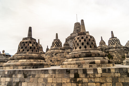 Ancient stone stupas of Borobudur, a UNESCO World Heritage Buddhist monument in Central Java, Indonesia, under an overcast sky.