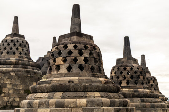 Ancient stone stupas of Borobudur, a UNESCO World Heritage Buddhist monument in Central Java, Indonesia, under an overcast sky.