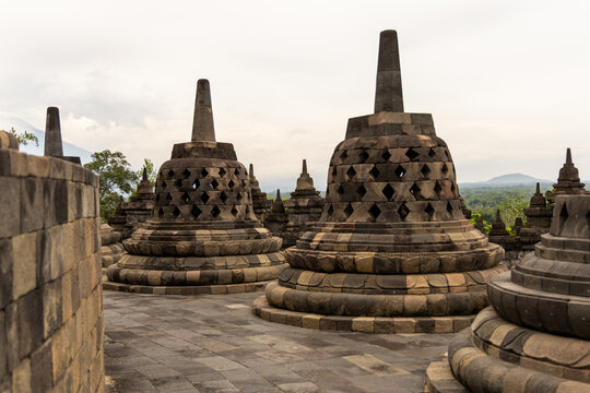 Ancient stone stupas of Borobudur, a UNESCO World Heritage Buddhist monument in Central Java, Indonesia, under an overcast sky.