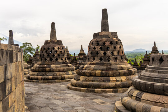 Ancient stone stupas of Borobudur, a UNESCO World Heritage Buddhist monument in Central Java, Indonesia, under an overcast sky.