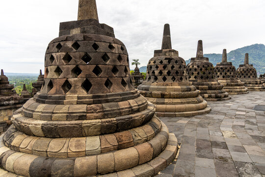 Ancient stone stupas of Borobudur, a UNESCO World Heritage Buddhist monument in Central Java, Indonesia, under an overcast sky.