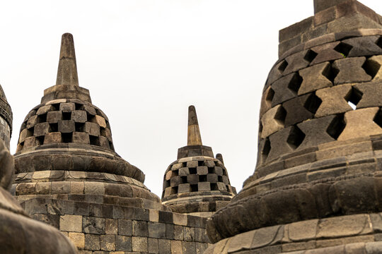 Ancient stone stupas of Borobudur, a UNESCO World Heritage Buddhist monument in Central Java, Indonesia, under an overcast sky.