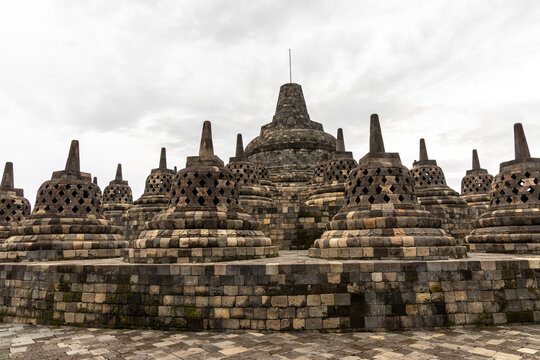 Ancient stone stupas of Borobudur, a UNESCO World Heritage Buddhist monument in Central Java, Indonesia, under an overcast sky.