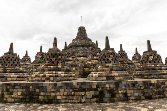 Ancient stone stupas of Borobudur, a UNESCO World Heritage Buddhist monument in Central Java, Indonesia, under an overcast sky.