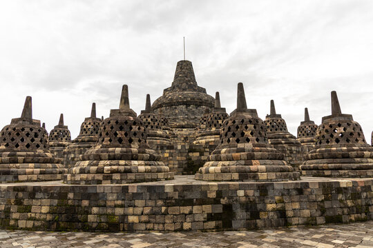 Ancient stone stupas of Borobudur, a UNESCO World Heritage Buddhist monument in Central Java, Indonesia, under an overcast sky.