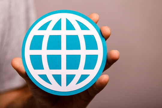 Close-up of a hand holding a blue globe symbol, representing worldwide connection.