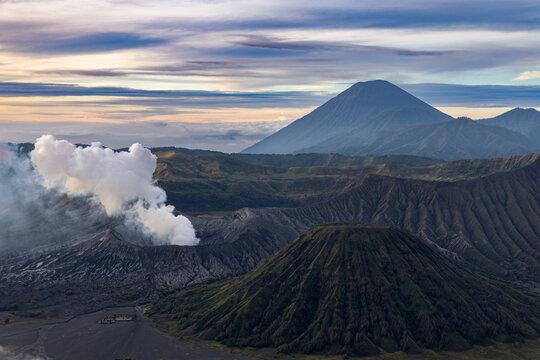Mount Bromo volcano at sunrise, viewed from King Kong viewpoint in Bromo Tengger Semeru National Park, East Java, Indonesia. Active crater smoke, Mount Semeru cone, clouds, and vast ash plain.