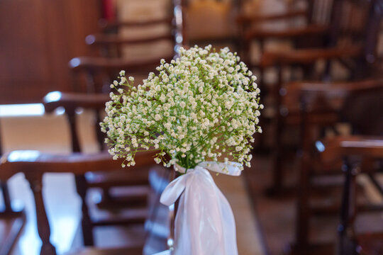 Bouquet of small white flowers tied with ribbon in a setting with wooden chairs