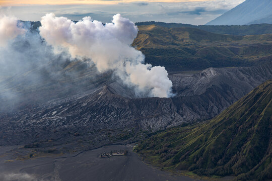 Mount Bromo volcano at sunrise, viewed from King Kong viewpoint in Bromo Tengger Semeru National Park, East Java, Indonesia. Active crater smoke, Mount Semeru cone, clouds, and vast ash plain.