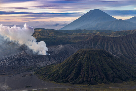 Mount Bromo volcano at sunrise, viewed from King Kong viewpoint in Bromo Tengger Semeru National Park, East Java, Indonesia. Active crater smoke, Mount Semeru cone, clouds, and vast ash plain.