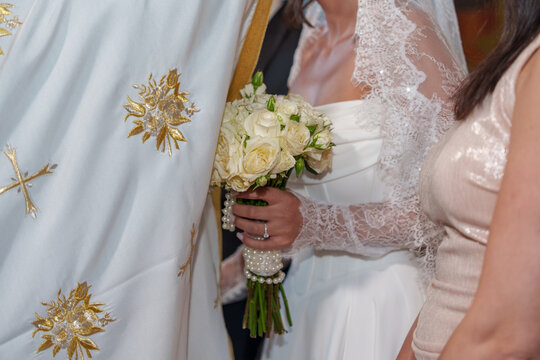 Wedding ceremony in a church with bride holding flowers and priest officiating