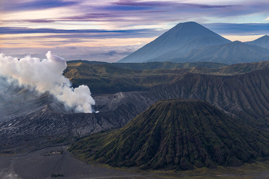 Mount Bromo volcano at sunrise, viewed from King Kong viewpoint in Bromo Tengger Semeru National Park, East Java, Indonesia. Active crater smoke, Mount Semeru cone, clouds, and vast ash plain.