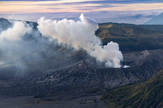 Mount Bromo volcano at sunrise, viewed from King Kong viewpoint in Bromo Tengger Semeru National Park, East Java, Indonesia. Active crater smoke, Mount Semeru cone, clouds, and vast ash plain.