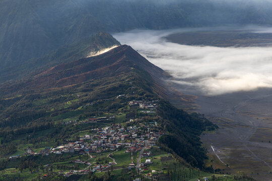 Mount Bromo volcano at sunrise, viewed from King Kong viewpoint in Bromo Tengger Semeru National Park, East Java, Indonesia. Active crater smoke, Mount Semeru cone, clouds, and vast ash plain.
