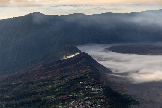 Mount Bromo volcano at sunrise, viewed from King Kong viewpoint in Bromo Tengger Semeru National Park, East Java, Indonesia. Active crater smoke, Mount Semeru cone, clouds, and vast ash plain.